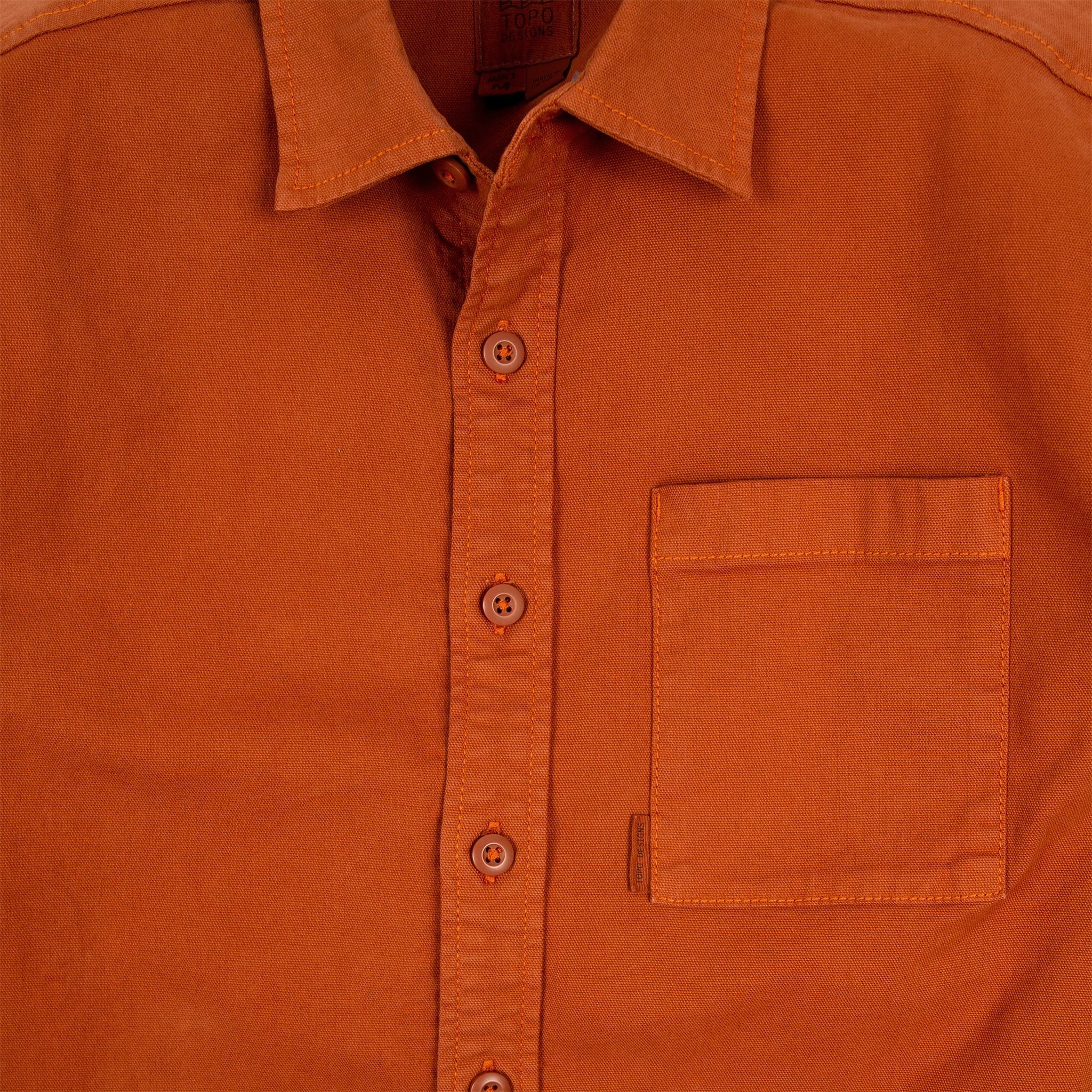 General detail shot of Topo Designs Men's Dirt Shirt in Brick orange showing buttons and chest pocket.