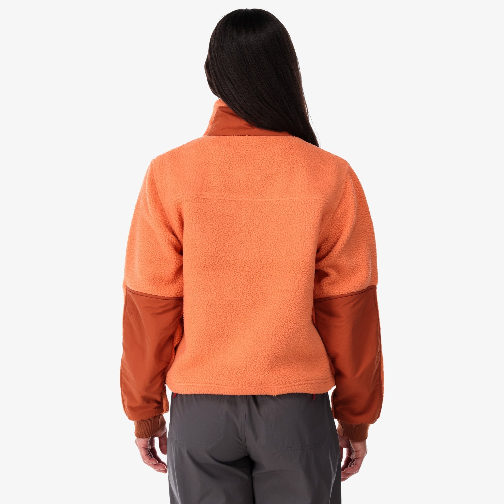 Back shot of Topo Designs Women's Mountain Fleece Pullover in "Rust / brick" pink orange on model.