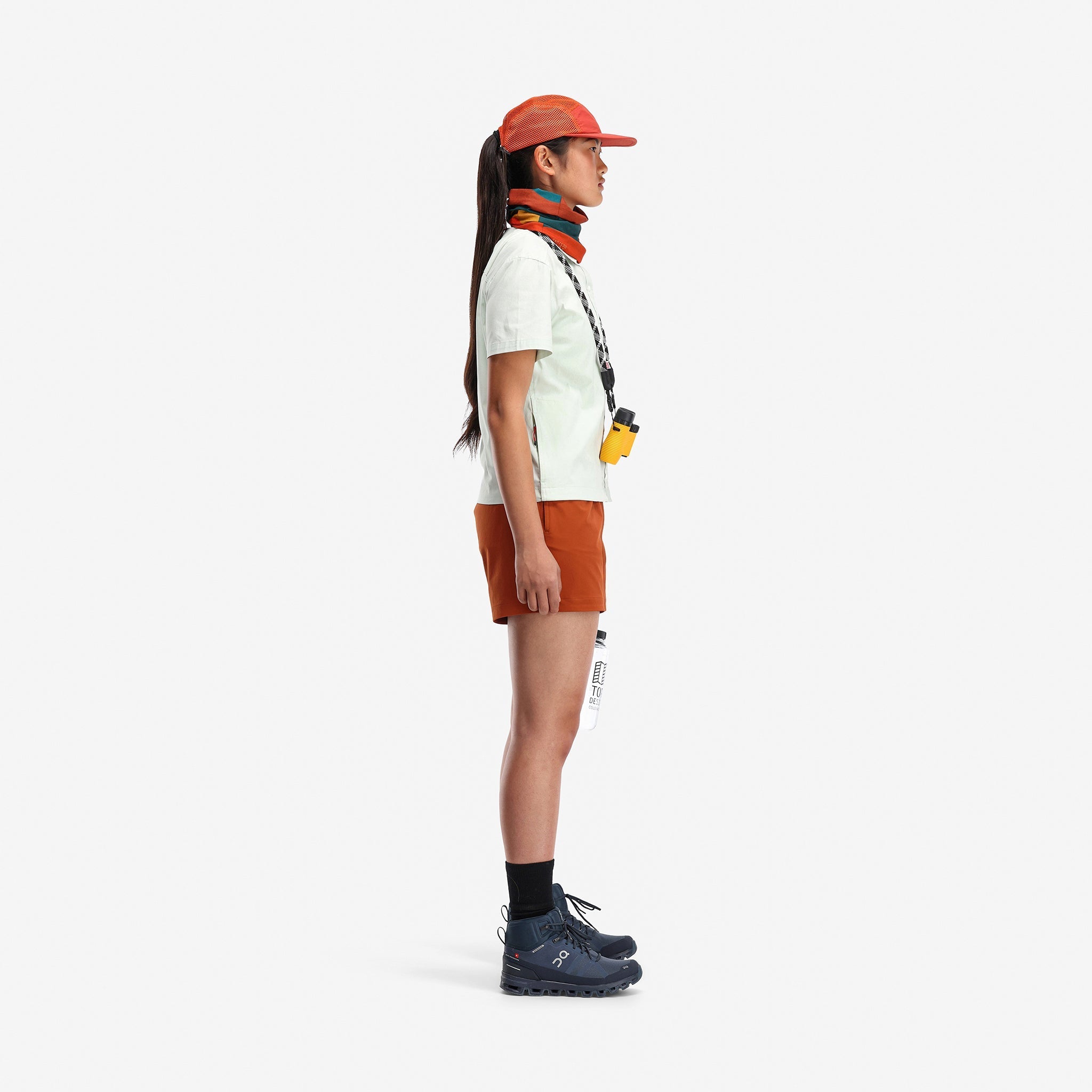 Side model shot of Topo Designs Women's Global lightweight quick dry travel Shorts in "Brick" orange.