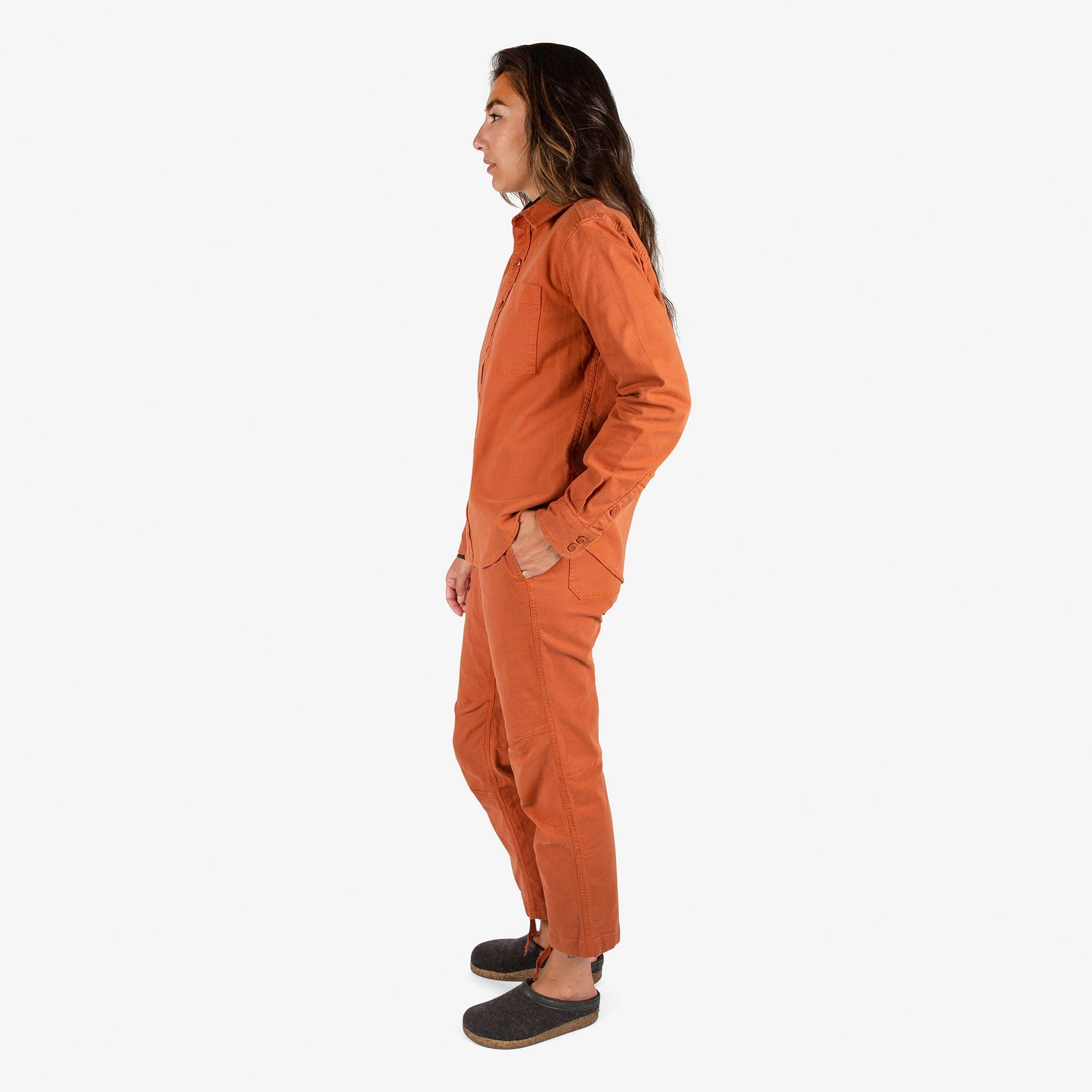 Side model shot of Topo Designs Women's Dirt Shirt & Pants in "Brick" orange.