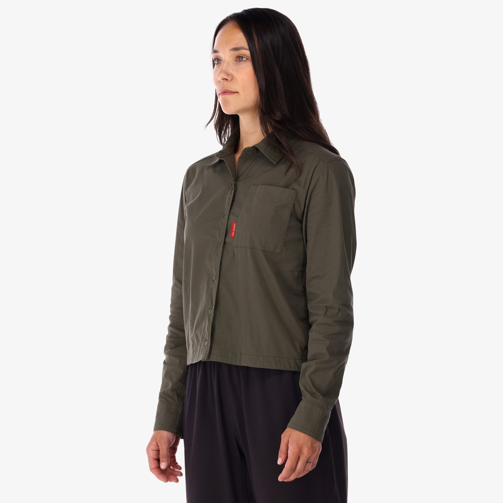 Side model shot of Topo Designs Women's Global long sleeve lightweight snap travel shirt in "olive" green on model front.