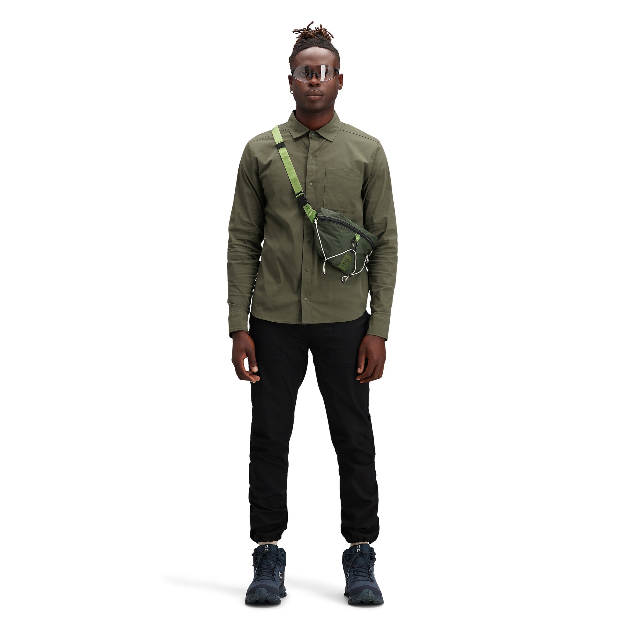 Model wearing Topo Designs Men's Global Shirt long sleeve lightweight travel snap shirt in "olive" green. Show on "Pond Blue".