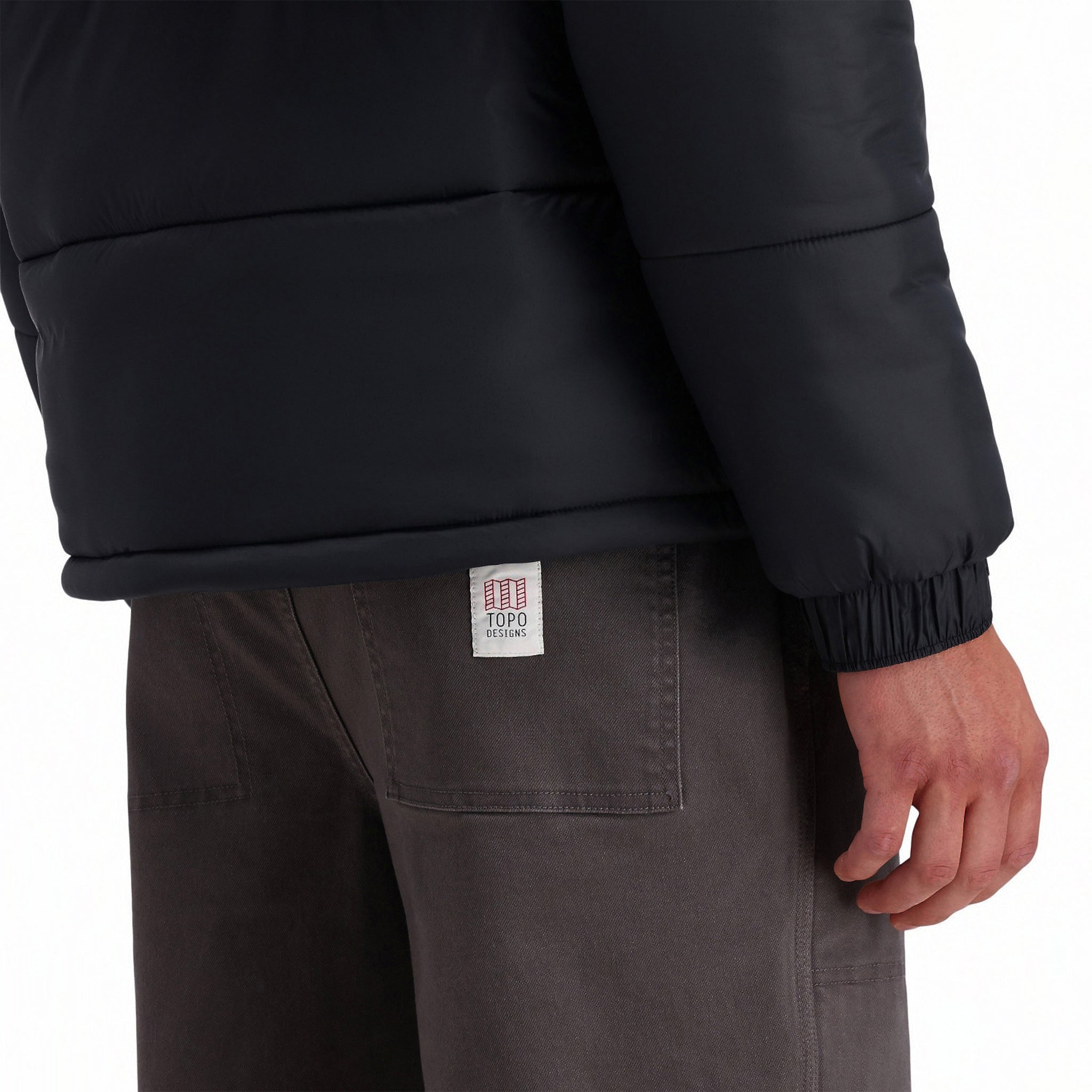 General back model detail shot of bottom hem and elastic cuffs on Topo Designs Men's Puffer recycled insulated Jacket in "Black"